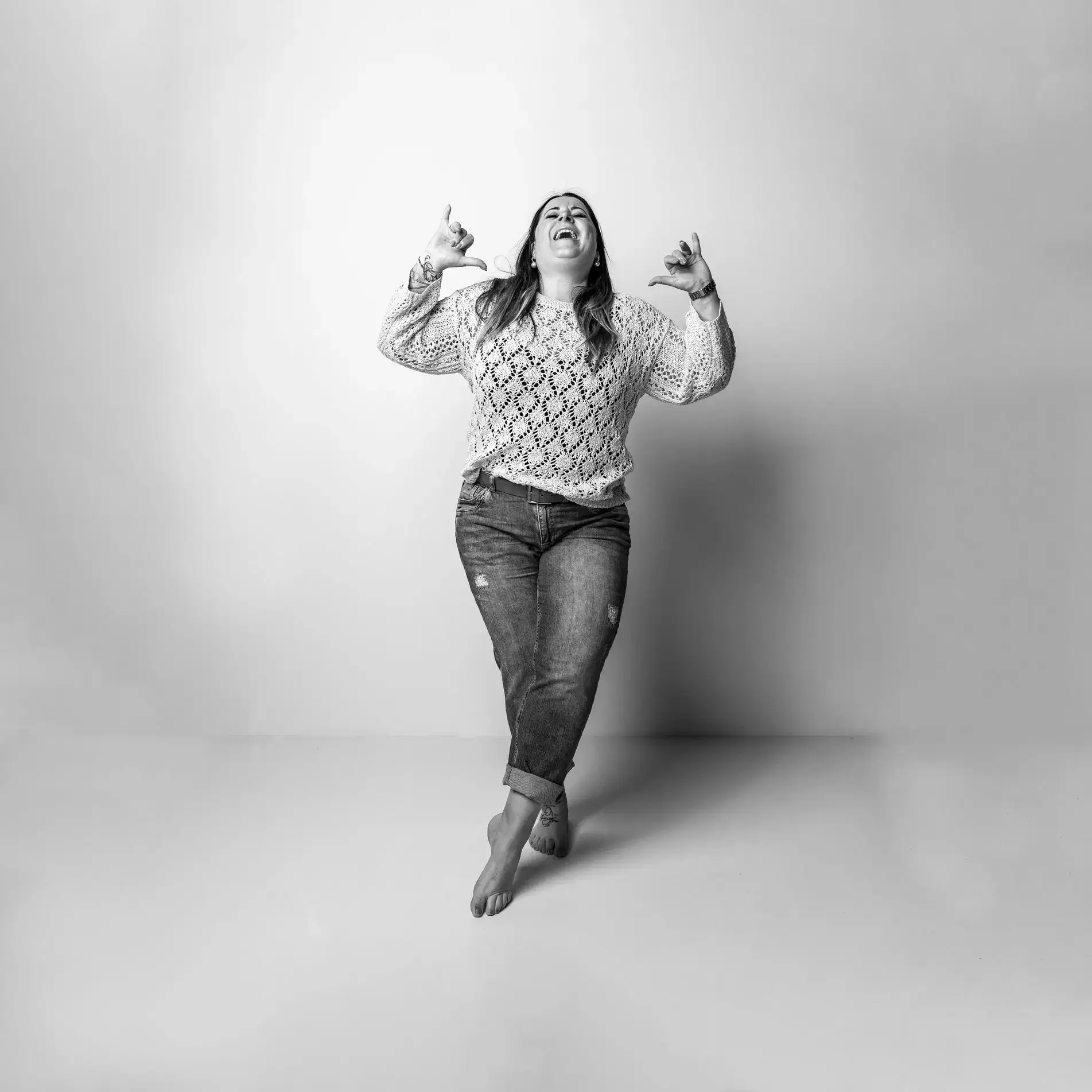 Schwarz-weiß-Porträt einer Frau, die barfuß auf einem Studio-Hintergrund tanzt und lacht – lebendig und authentisch eingefangen bei einem Fotoshooting in Dresden im TRU Fotostudio.